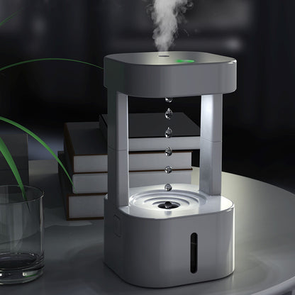 Anti-gravity water drop humidifier with mist spray on a table in a dimly lit room.